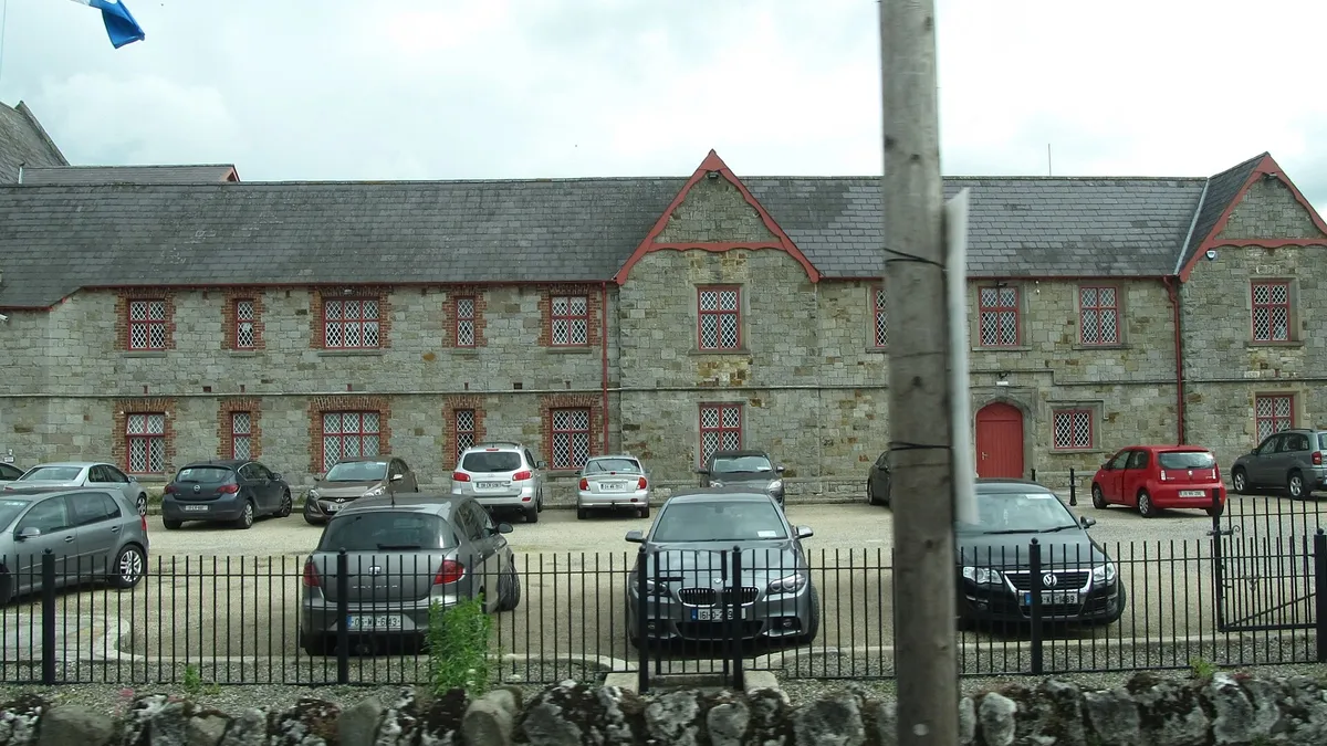 The long two storey stone front of Carrickmacross Workhouse behind its railings
