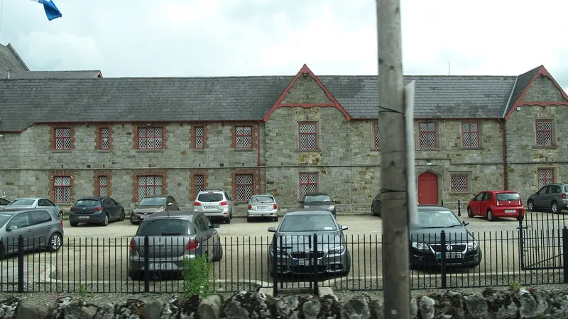 The long two storey stone front of Carrickmacross Workhouse behind its railings