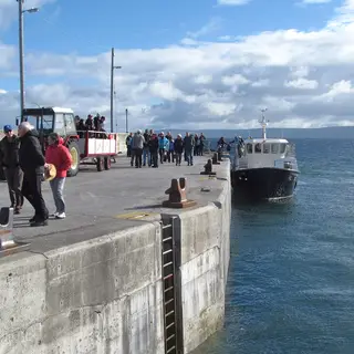 Passengers walking along the pier as the ferry comes in to Inis Oirr