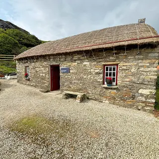 A thatched stone cottage with a red door at the Glencolmcille Folk Village