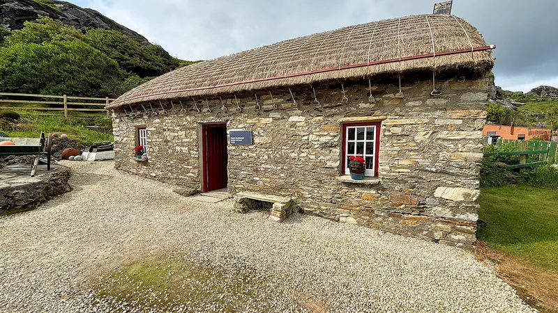 A thatched stone cottage with a red door at the Glencolmcille Folk Village