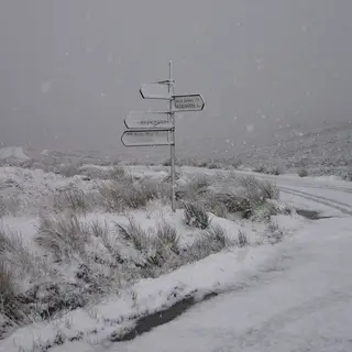 A signpost and a snow covered road crossing the bog at the Sally Gap