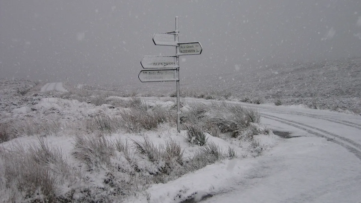A signpost and a snow covered road crossing the bog at the Sally Gap