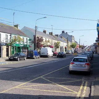 A street of shopfronts and parked cars running through Ballyconnell