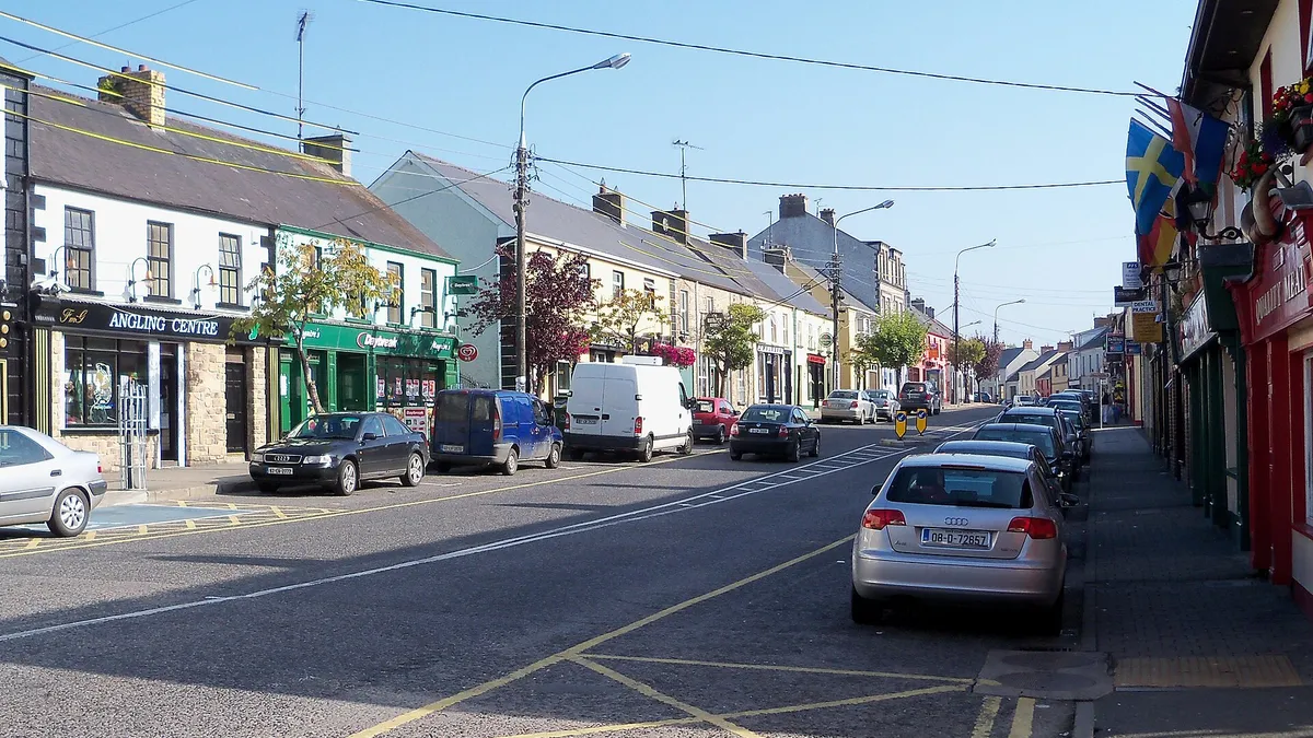 A street of shopfronts and parked cars running through Ballyconnell