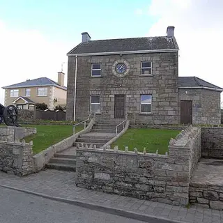 The stone Memorial Hall at Ballinamuck with a cannon on the grass beside it