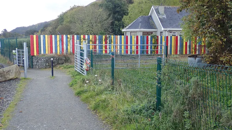 A brightly striped fence along the Carlingford Greenway where the path passes a school