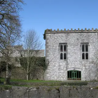 The stone hall and castle buildings at Newcastle West behind their lawn