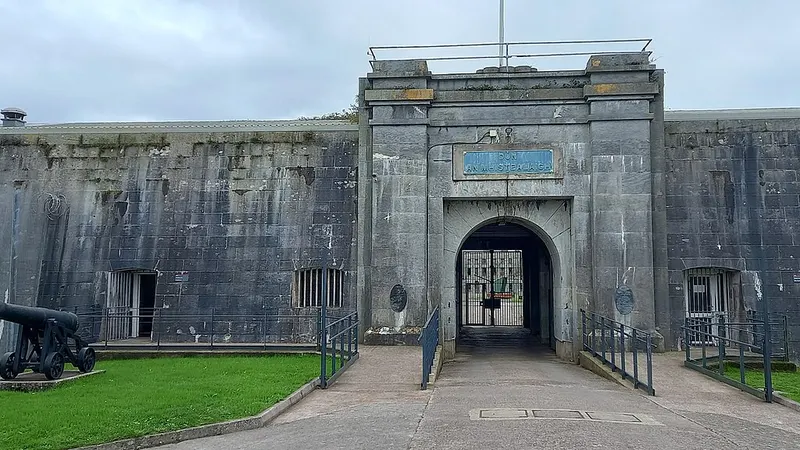 The arched stone gateway into Fort Mitchel on Spike Island, with a cannon on the grass beside it