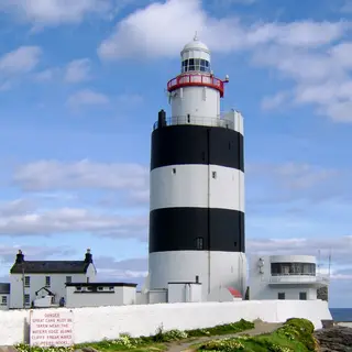 The black and white banded tower of Hook Lighthouse against a blue sky