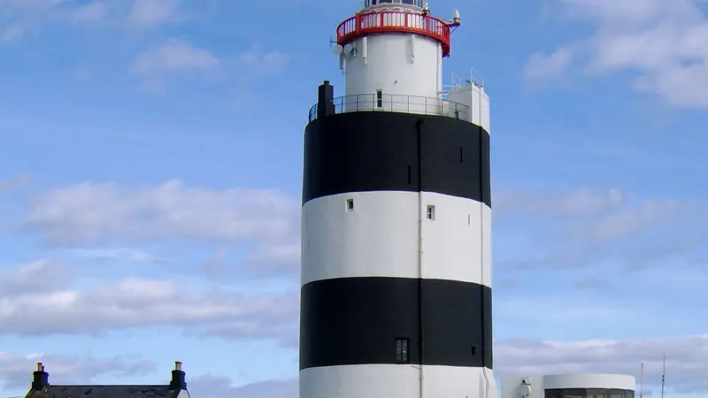 The black and white banded tower of Hook Lighthouse against a blue sky