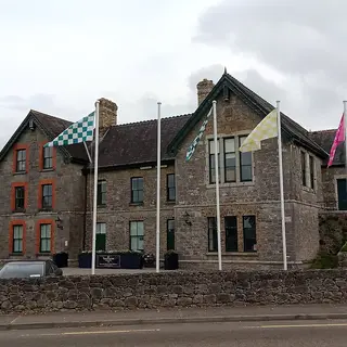 The stone front of Abbeyleix Heritage House with flags outside it