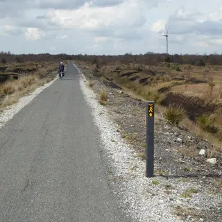 A cyclist on the long straight bog road through Lough Boora Discovery Park