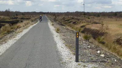 A cyclist on the long straight bog road through Lough Boora Discovery Park