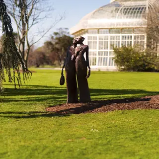 A statue on the lawn in front of the curved glasshouses at the National Botanic Gardens