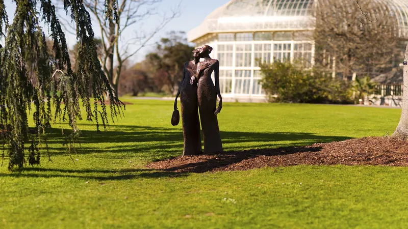 A statue on the lawn in front of the curved glasshouses at the National Botanic Gardens