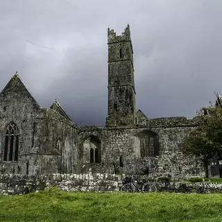The ruins and central tower of Quin Abbey under a heavy grey sky