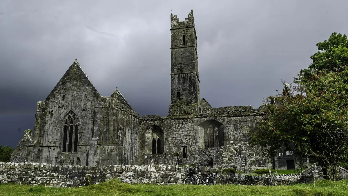 The ruins and central tower of Quin Abbey under a heavy grey sky