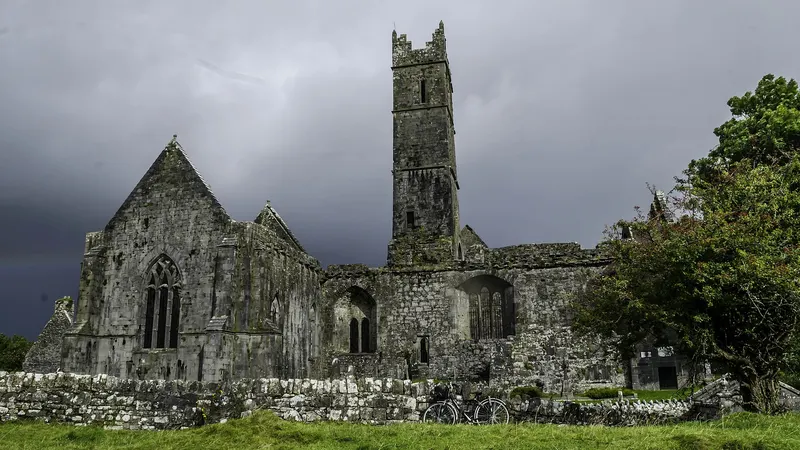 The ruins and central tower of Quin Abbey under a heavy grey sky