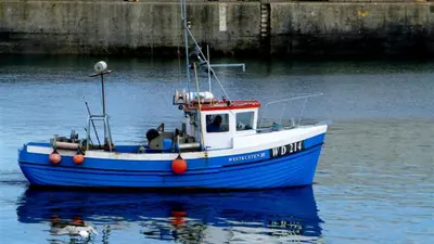 A blue fishing boat lying against the harbour wall at Kilmore Quay