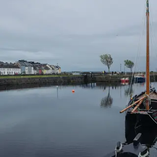 Sailing boats moored in Galway harbour with the old buildings behind them