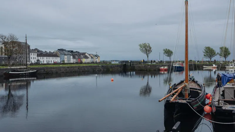 Sailing boats moored in Galway harbour with the old buildings behind them