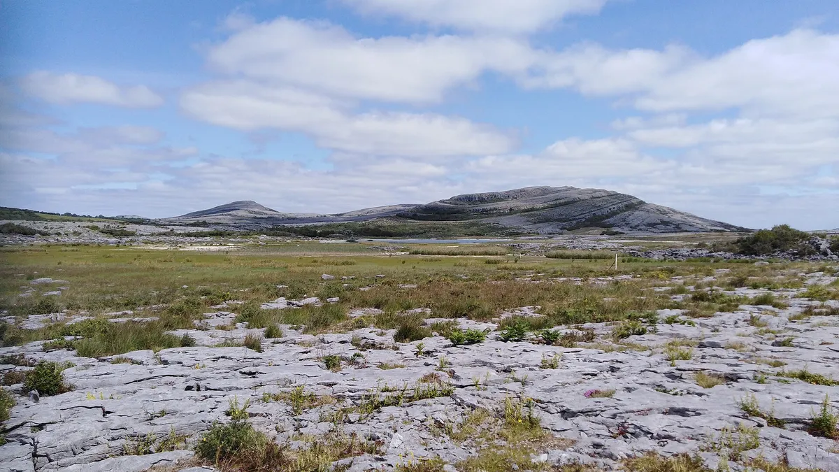 Bare limestone pavement in the Burren with the hill of Mullaghmore behind